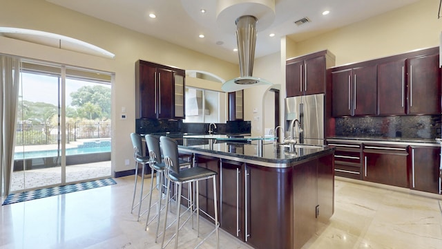 401 SE Verada Ave, Port Saint Lucie, FL 34983 - kitchen with dark brown cabinets, stainless steel fridge, tasteful backsplash, a kitchen island with sink, and recessed lighting