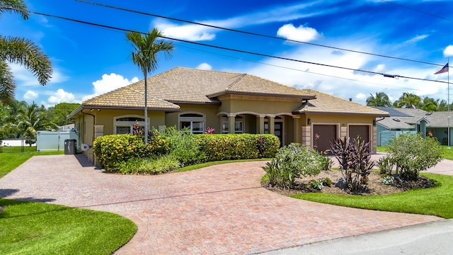 401 SE Verada Ave, Port Saint Lucie, FL 34983 - mediterranean / spanish home featuring a garage, a tile roof, stucco siding, and decorative driveway