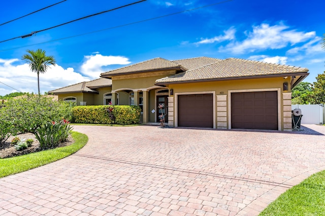 401 SE Verada Ave, Port Saint Lucie, FL 34983 - view of front of property with curved driveway, an attached garage, stucco siding, and a tiled roof