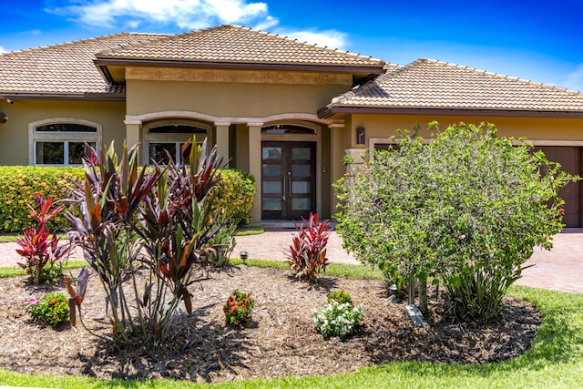 401 SE Verada Ave, Port Saint Lucie, FL 34983 - view of front of home featuring french doors, a garage, a tile roof, and stucco siding