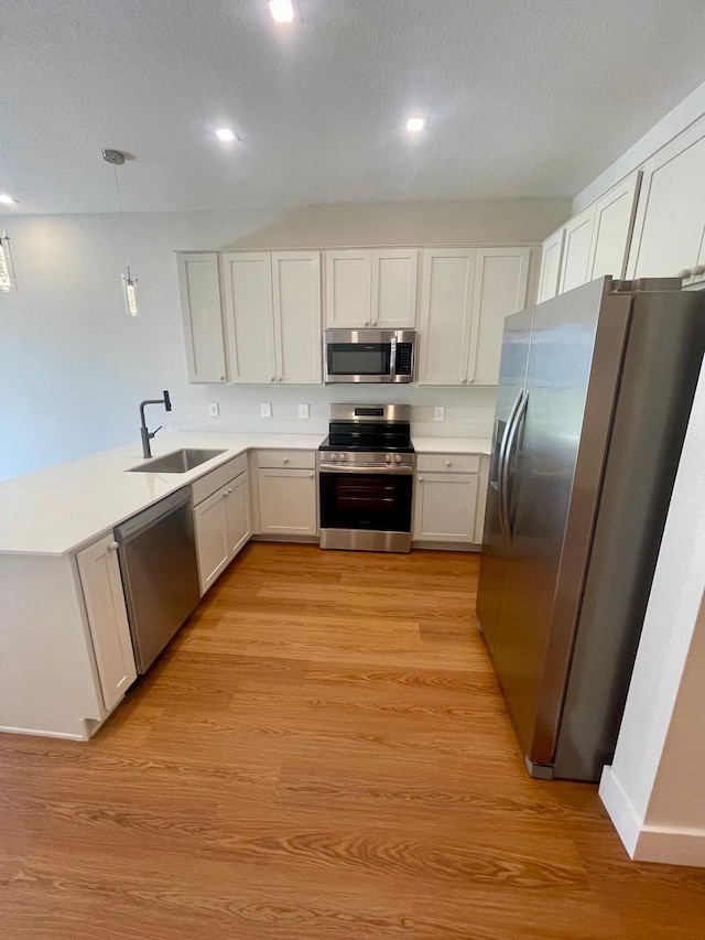 6159 Peaceful Park Way, Clermont, FL 34714 - kitchen featuring appliances with stainless steel finishes, a sink, a peninsula, light wood-style flooring, and light countertops