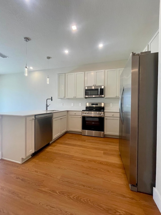 6159 Peaceful Park Way, Clermont, FL 34714 - kitchen featuring stainless steel appliances, a peninsula, decorative light fixtures, a sink, and light wood finished floors