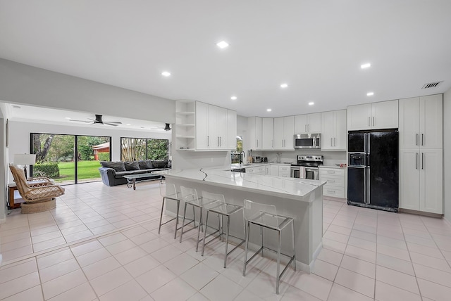 6170 Brandon St, Palm Beach Gardens, FL 33418 - kitchen featuring stainless steel appliances, open shelves, a peninsula, a kitchen bar, and light tile patterned flooring