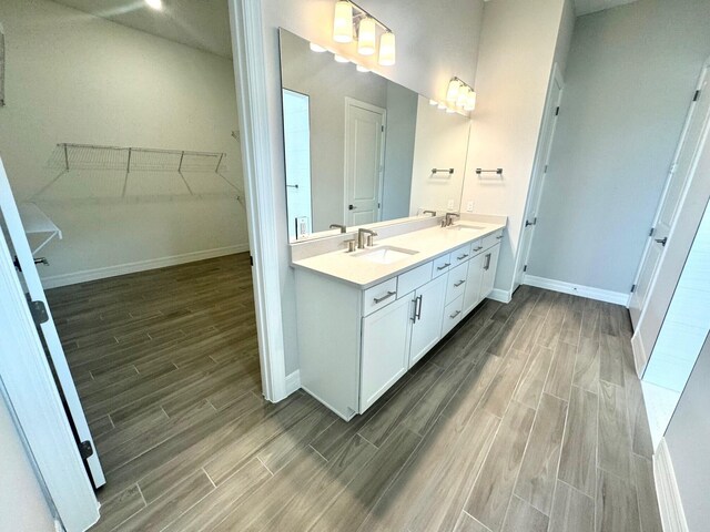 10710 Stellar Cir Unit 03, Palm Beach Gardens, FL 33412 - bathroom featuring wood finish floors, double vanity, baseboards, and a spacious closet