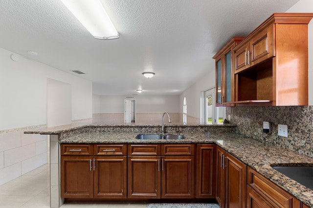 6057 Ridgelake Cir, Vero Beach, FL 32967 - kitchen with a sink, stone counters, tile walls, wainscoting, and a peninsula
