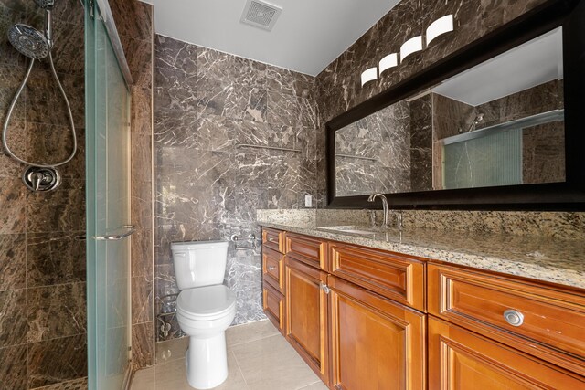 6057 Ridgelake Cir, Vero Beach, FL 32967 - bathroom featuring tile walls, vanity, toilet, a stall shower, and tile patterned flooring