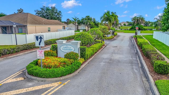 6057 Ridgelake Cir, Vero Beach, FL 32967 - view of asphalt road featuring traffic signs, curbs, a residential view, and a gated entry