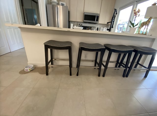 9124 Sun Terrace Cir Unit D, West Palm Beach, FL 33403 - kitchen with stainless steel appliances, a breakfast bar, and light tile patterned floors