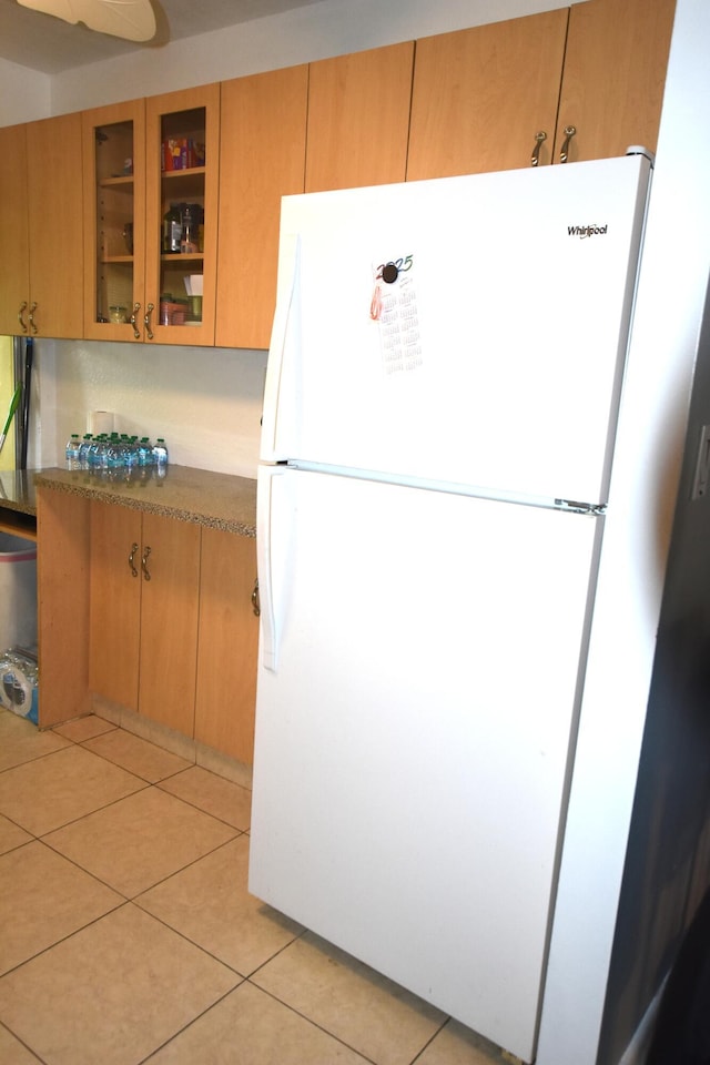 251 NW 76th Ave Unit 105, Margate, FL 33063 - kitchen with freestanding refrigerator, glass insert cabinets, and light tile patterned flooring
