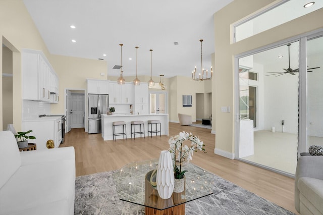 6845 Big Cypress Dr, Jupiter, FL 33458 - living room with light wood finished floors, a towering ceiling, a ceiling fan, a chandelier, and recessed lighting
