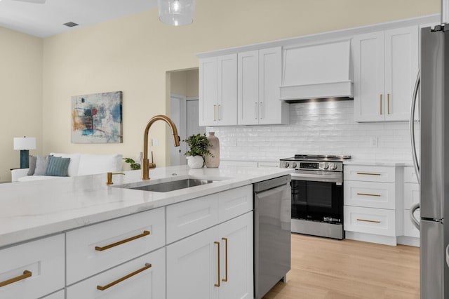 6845 Big Cypress Dr, Jupiter, FL 33458 - kitchen with stainless steel appliances, custom exhaust hood, tasteful backsplash, white cabinets, and light stone counters