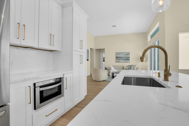 6845 Big Cypress Dr, Jupiter, FL 33458 - kitchen with open floor plan, light wood-style floors, white cabinets, light stone counters, and appliances with stainless steel finishes