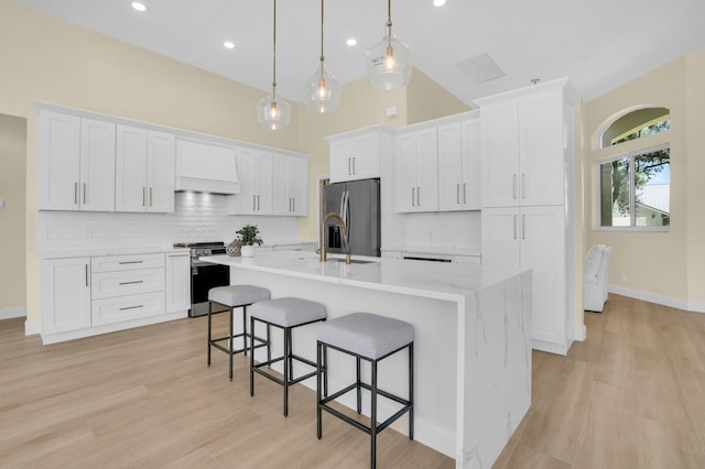 6845 Big Cypress Dr, Jupiter, FL 33458 - kitchen with stainless steel appliances, a breakfast bar area, a center island with sink, white cabinetry, and recessed lighting