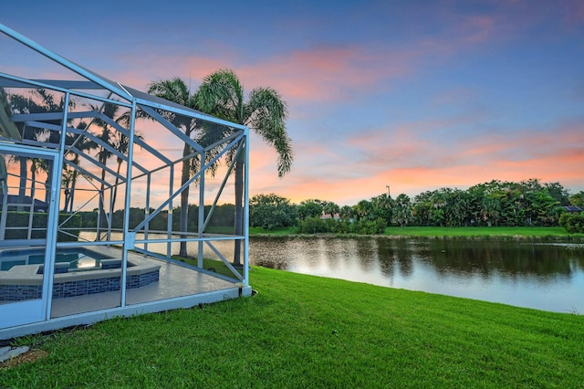 6845 Big Cypress Dr, Jupiter, FL 33458 - yard at dusk featuring glass enclosure, a water view, a lawn, an in-ground hot tub, and an outdoor pool