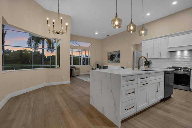 6845 Big Cypress Dr, Jupiter, FL 33458 - kitchen with stainless steel appliances, light wood-type flooring, a chandelier, light stone counters, and white cabinets