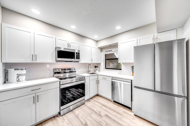 8641 Boca Glades D Blvd W Unit D, Boca Raton, FL 33434 - kitchen with appliances with stainless steel finishes, light wood-type flooring, light countertops, backsplash, and white cabinets