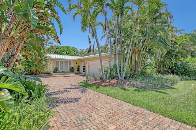 134 Worth Ct N, West Palm Beach, FL 33405 - view of front of property featuring a garage, decorative driveway, a standing seam roof, metal roof, and a front lawn
