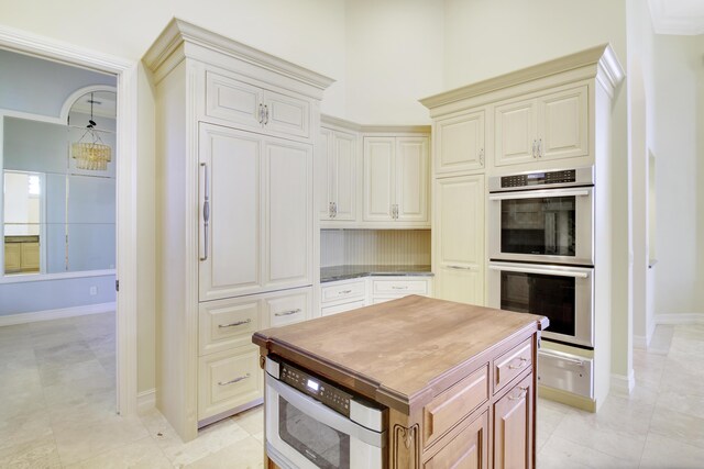 1186 Breakers W Blvd, West Palm Beach, FL 33411 - kitchen with double oven, a warming drawer, baseboards, cream cabinets, and a center island