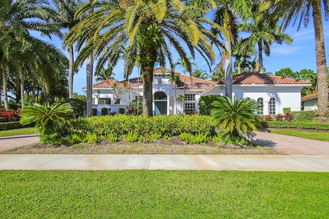 1186 Breakers W Blvd, West Palm Beach, FL 33411 - mediterranean / spanish house featuring a tiled roof, a front yard, and stucco siding