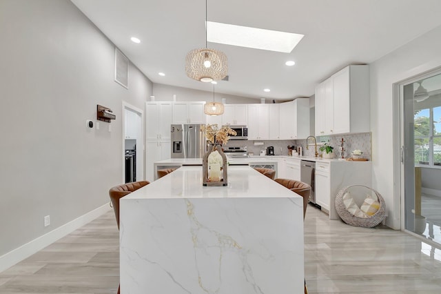 298 Las Palmas St, Royal Palm Beach, FL 33411 - kitchen with appliances with stainless steel finishes, a center island, tasteful backsplash, a skylight, and white cabinets