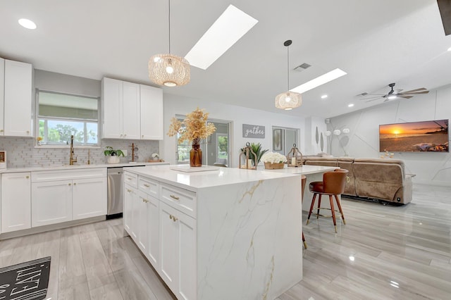 298 Las Palmas St, Royal Palm Beach, FL 33411 - kitchen featuring a skylight, vaulted ceiling, a sink, open floor plan, and white cabinetry