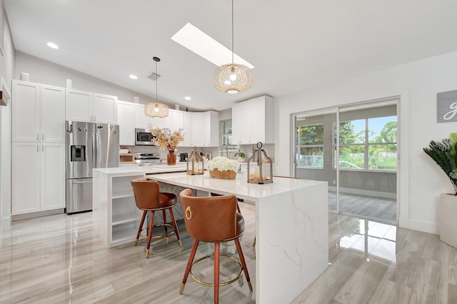 298 Las Palmas St, Royal Palm Beach, FL 33411 - kitchen with stainless steel appliances, a skylight, tasteful backsplash, vaulted ceiling, and white cabinetry
