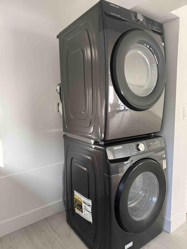 3056 NE 14th Ave, Oakland Park, FL 33334 - laundry room featuring stacked washer / drying machine, baseboards, and light wood-style floors