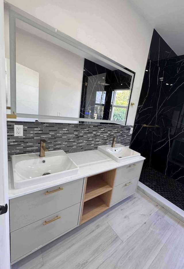 3056 NE 14th Ave, Oakland Park, FL 33334 - full bathroom featuring double vanity, a marble finish shower, wood finished floors, and tasteful backsplash