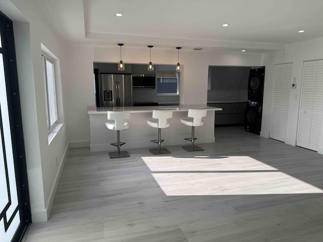 3056 NE 14th Ave, Oakland Park, FL 33334 - kitchen featuring stacked washer and clothes dryer, appliances with stainless steel finishes, a kitchen breakfast bar, a peninsula, and baseboards