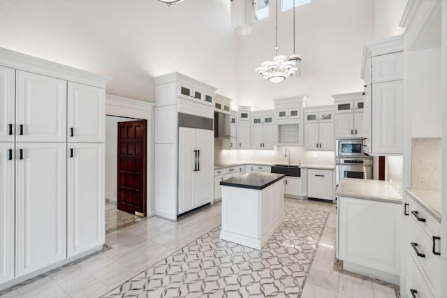4700 Sanctuary Ln, Boca Raton, FL 33431 - kitchen featuring built in appliances, a high ceiling, white cabinetry, a chandelier, and pendant lighting