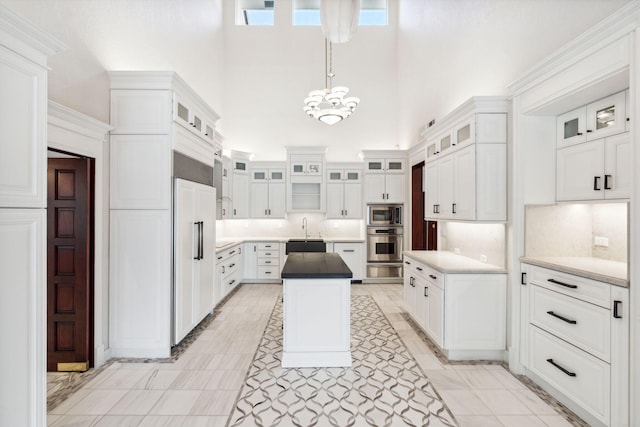 4700 Sanctuary Ln, Boca Raton, FL 33431 - kitchen with built in appliances, a towering ceiling, a chandelier, white cabinets, and a center island