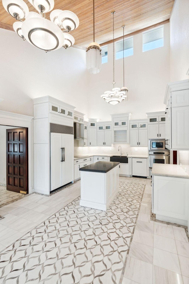 4700 Sanctuary Ln, Boca Raton, FL 33431 - kitchen with built in appliances, a high ceiling, white cabinetry, a kitchen island, and hanging light fixtures