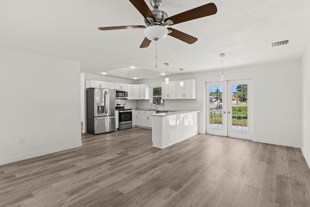 798 SE Atlantus Ave, Port Saint Lucie, FL 34983 - kitchen with stainless steel appliances, a peninsula, french doors, white cabinets, and light countertops