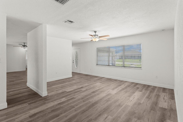 798 SE Atlantus Ave, Port Saint Lucie, FL 34983 - unfurnished living room with ceiling fan, wood finished floors, baseboards, and a textured ceiling