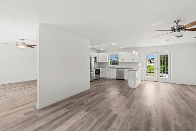 798 SE Atlantus Ave, Port Saint Lucie, FL 34983 - unfurnished living room featuring a ceiling fan, light wood finished floors, and baseboards