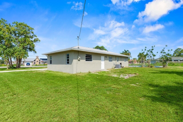 798 SE Atlantus Ave, Port Saint Lucie, FL 34983 - view of property exterior featuring central air condition unit, a lawn, and stucco siding