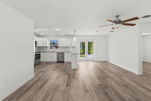 798 SE Atlantus Ave, Port Saint Lucie, FL 34983 - kitchen with stainless steel appliances, french doors, baseboards, white cabinetry, and a textured ceiling