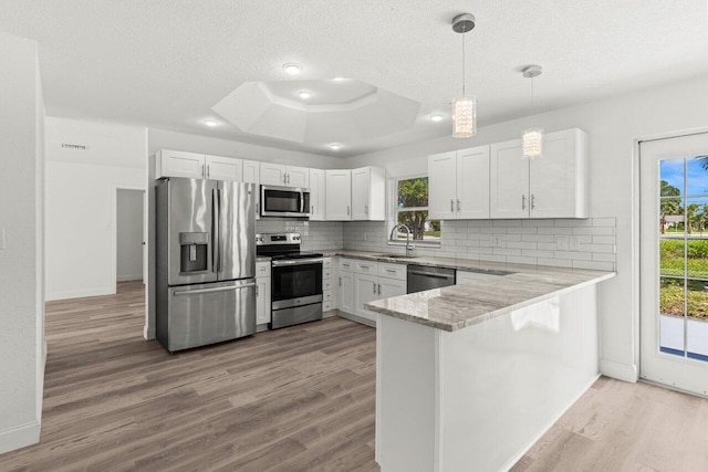 798 SE Atlantus Ave, Port Saint Lucie, FL 34983 - kitchen with appliances with stainless steel finishes, a sink, backsplash, a peninsula, and a textured ceiling