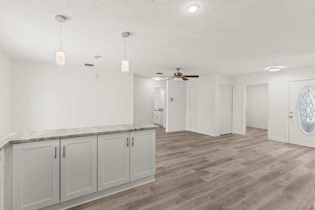 798 SE Atlantus Ave, Port Saint Lucie, FL 34983 - kitchen with ceiling fan, a textured ceiling, light wood-style flooring, decorative light fixtures, and baseboards