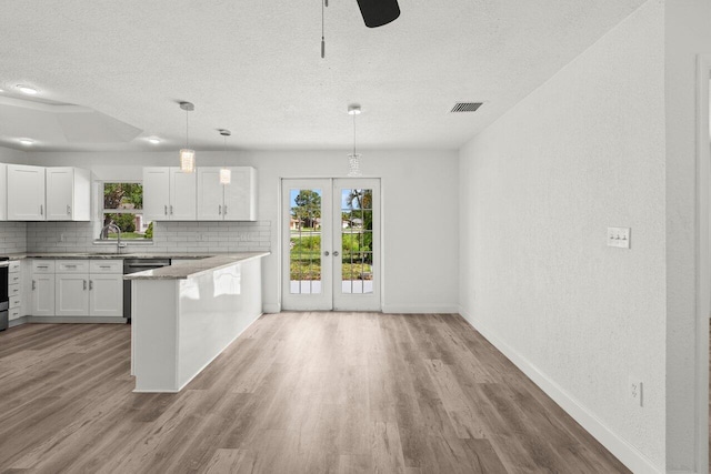 798 SE Atlantus Ave, Port Saint Lucie, FL 34983 - kitchen with a textured ceiling, baseboards, decorative backsplash, wood finished floors, and healthy amount of natural light