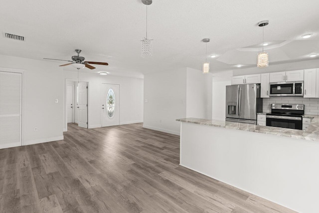 798 SE Atlantus Ave, Port Saint Lucie, FL 34983 - kitchen featuring stainless steel appliances, wood finished floors, ceiling fan, decorative backsplash, and a textured ceiling