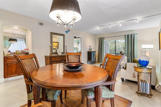 5200 E Club Cir Unit 106, Boca Raton, FL 33487 - dining area featuring a chandelier, arched walkways, light wood-type flooring, and a textured ceiling