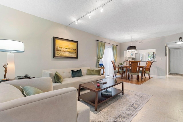 5200 E Club Cir Unit 106, Boca Raton, FL 33487 - living area with rail lighting, a textured ceiling, baseboards, and light wood finished floors