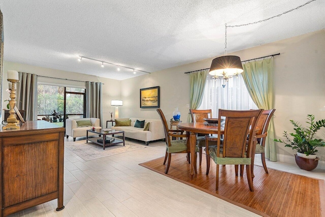 5200 E Club Cir Unit 106, Boca Raton, FL 33487 - dining space featuring a textured ceiling, light wood finished floors, track lighting, and a chandelier