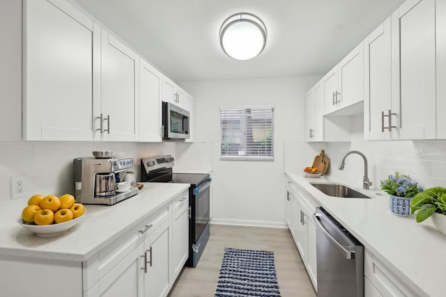 1803 NE 29th Pl, Ocala, FL 34479 - kitchen featuring stainless steel appliances, a sink, decorative backsplash, light wood-style flooring, and white cabinetry