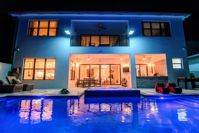 8305 Fishhawk Falls Ct, Boca Raton, FL 33496 - back of house at twilight featuring a ceiling fan, stucco siding, a patio area, and an outdoor pool