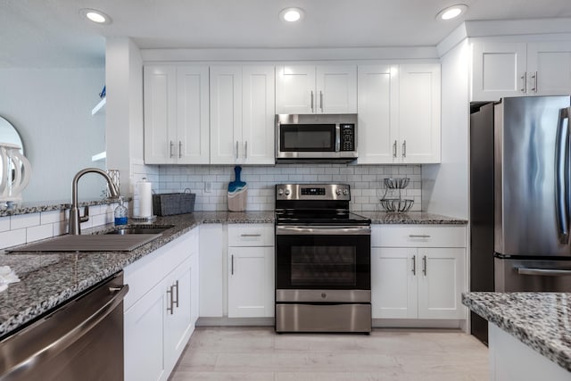 7430 S Ocean Dr Unit 518, Jensen Beach, FL 34957 - kitchen with stainless steel appliances, a sink, white cabinetry, light stone counters, and backsplash