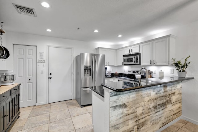 5285 SE Jennings Ln, Stuart, FL 34997 - kitchen featuring appliances with stainless steel finishes, a peninsula, recessed lighting, light tile patterned flooring, and baseboards