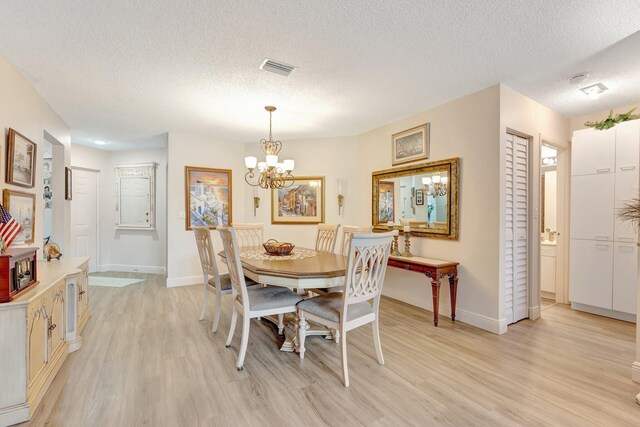 4101 Coral Tree Cir Unit 116, Coconut Creek, FL 33073 - dining area featuring light wood finished floors, baseboards, a textured ceiling, and a chandelier