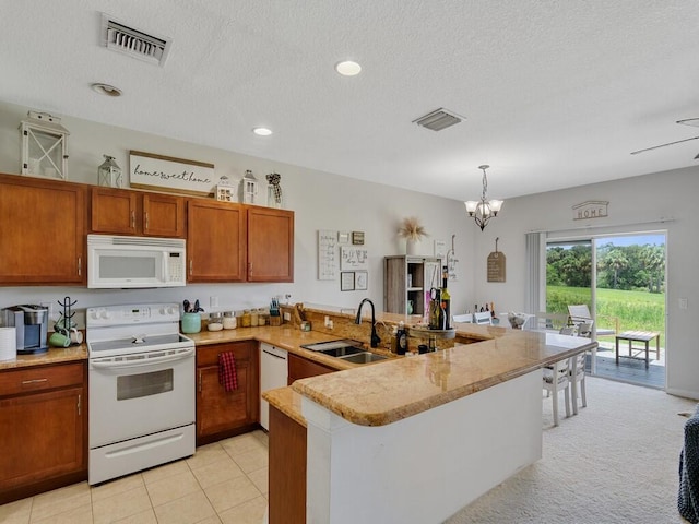 2536 Creekside Dr, Fort Pierce, FL 34981 - kitchen featuring white appliances, a sink, a peninsula, brown cabinets, and a chandelier